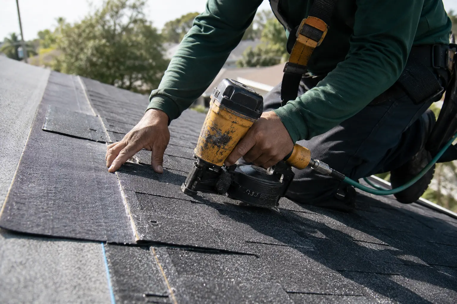 Roof Repair in Miami showing contractor installing asphalt shingles with roofing tools in natural sunlight